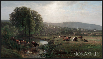 Pastoral landscape with cows grazing beside a calm stream, green trees, and distant hills.