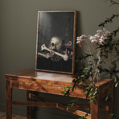 Framed artwork of a skull on a wooden table with a plant in the foreground.