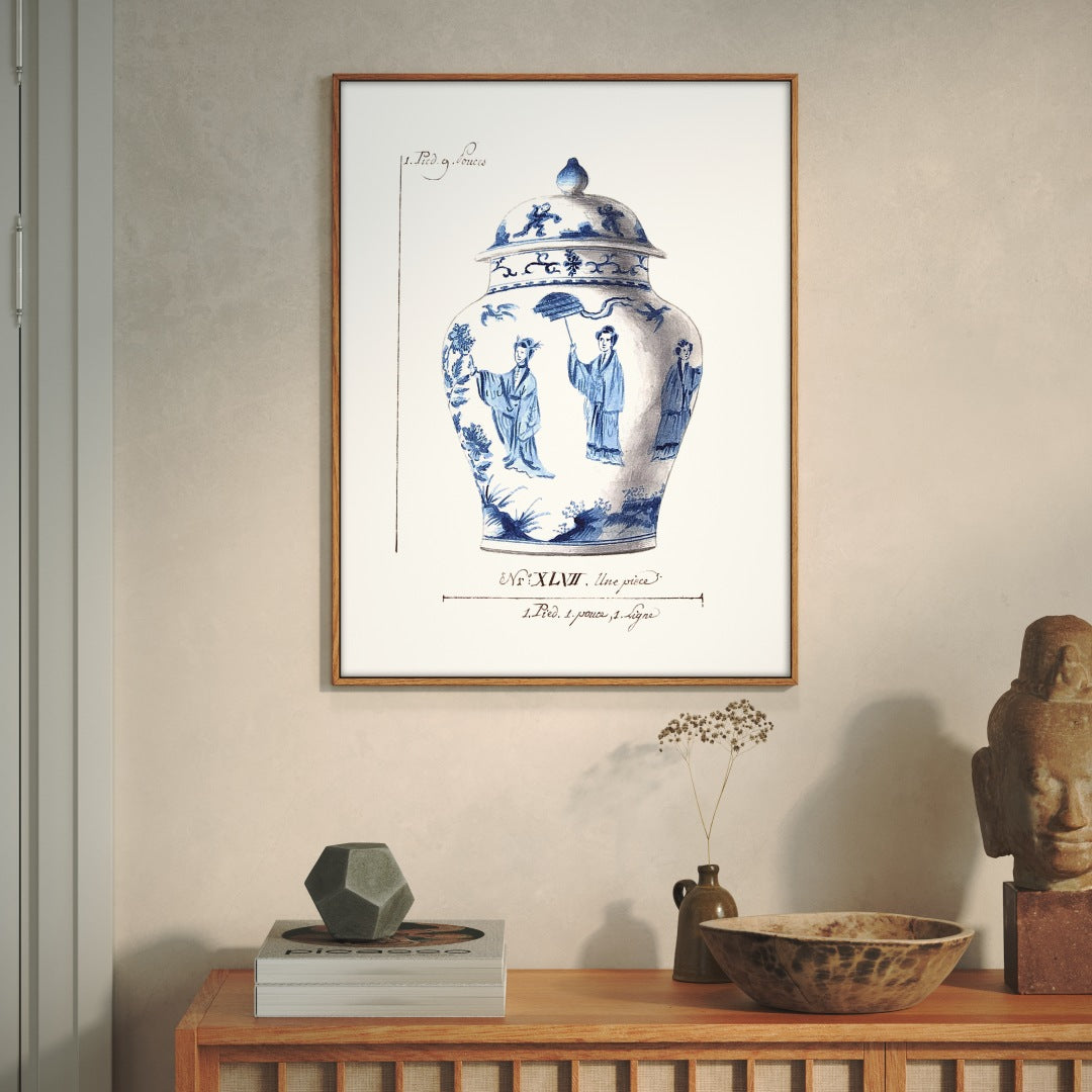 Framed artwork of a blue and white ceramic jar on a wall above a wooden furniture with decorative items.