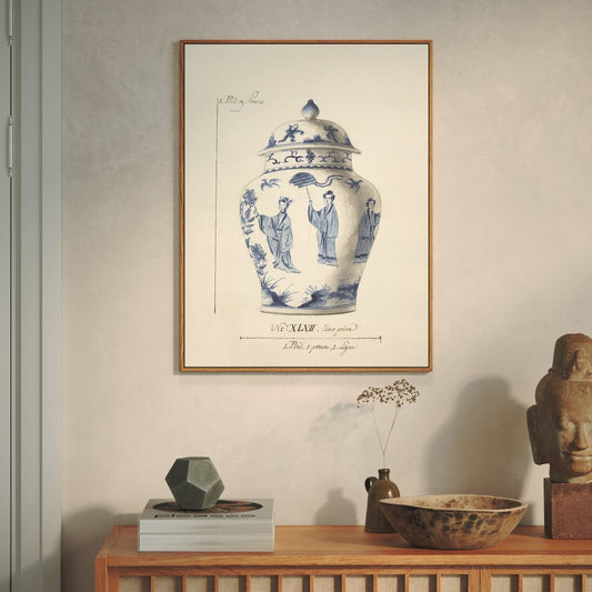 Framed artwork of a blue and white ceramic jar on a wall above a wooden shelf with decorative items.