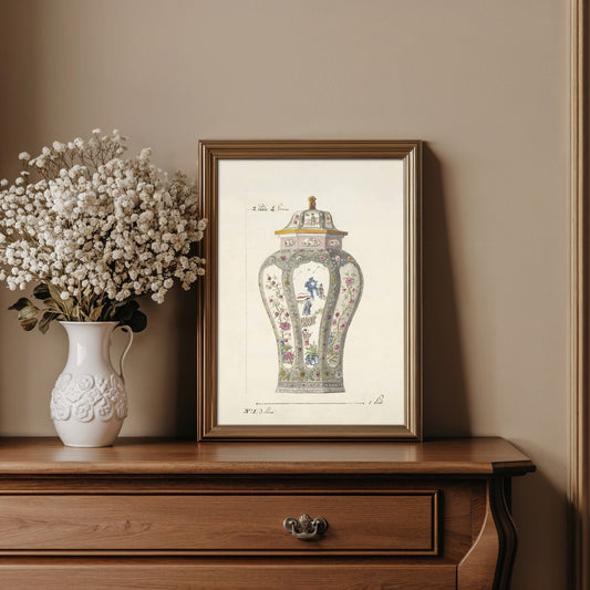 Framed artwork of a decorative vase on a wooden dresser with a vase of white flowers.