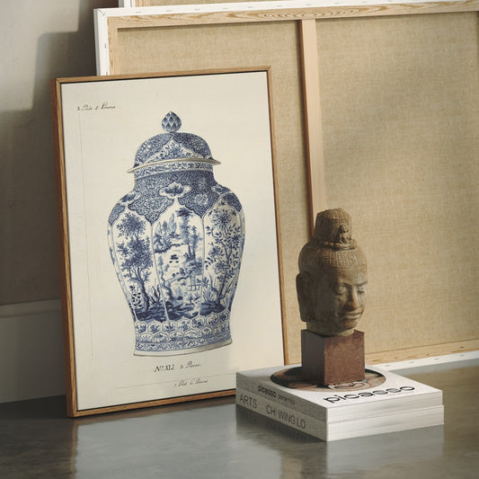 Framed artwork of a blue and white vase next to a sculpture on a stand.